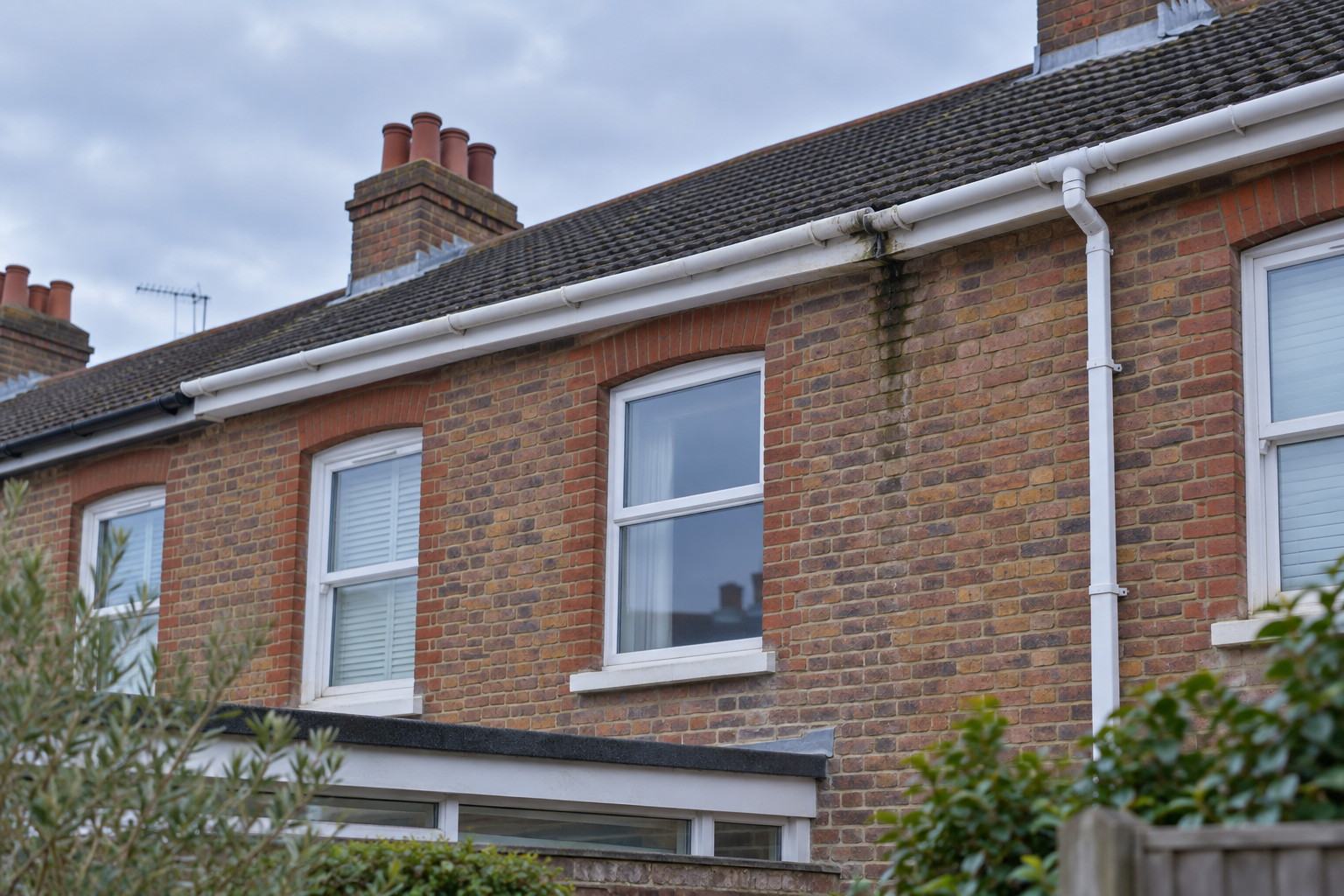 Slightly sagging white guttering along a brick Portsmouth terrace roofline